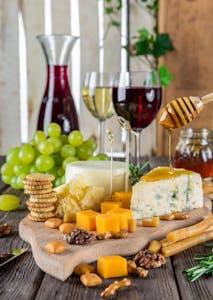 Sophisticated cheese platter with assorted wines, grapes, honey, and nuts.